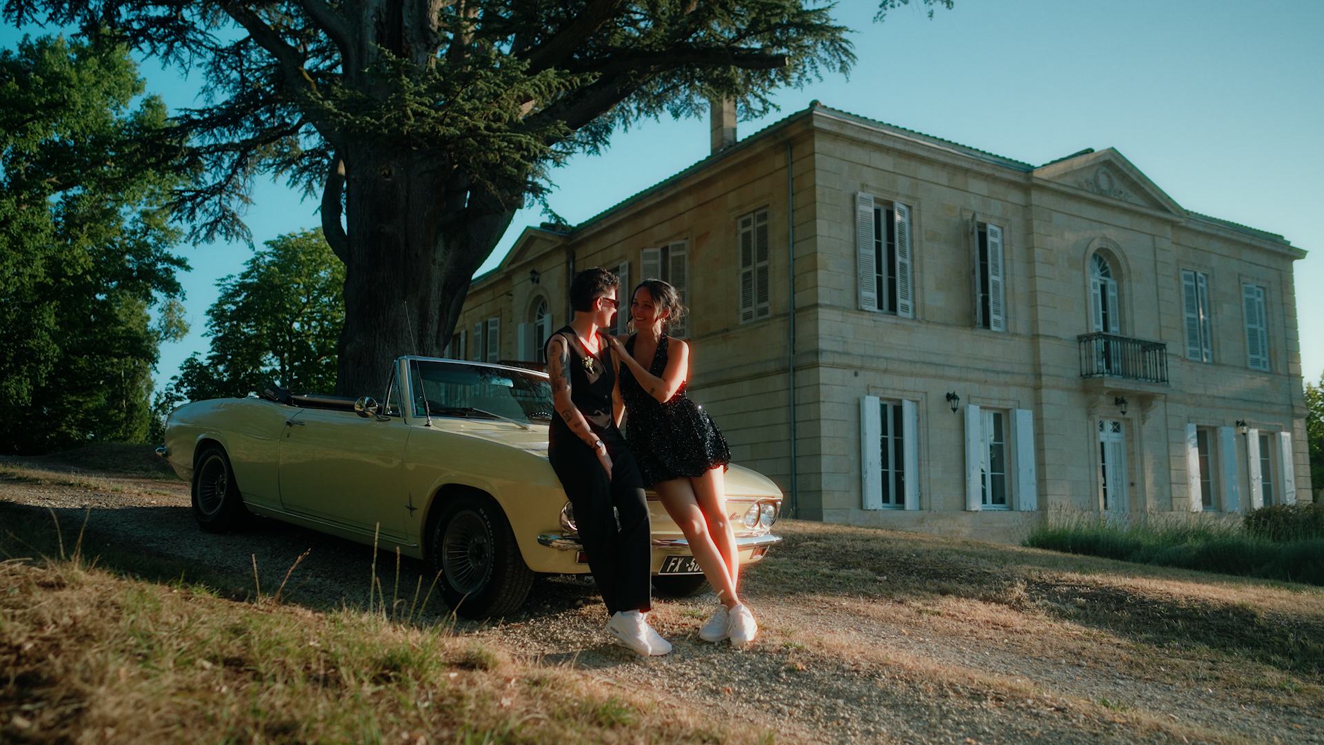 Laura et Marie posent avec leur voiture de collection devant le Château Erigoye.