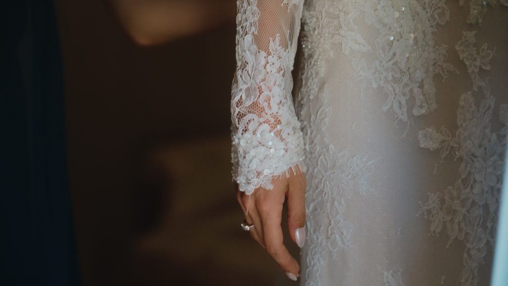 Détail de la robe en dentelle de Justine pendant les préparatifs de son mariage dans les Landes.